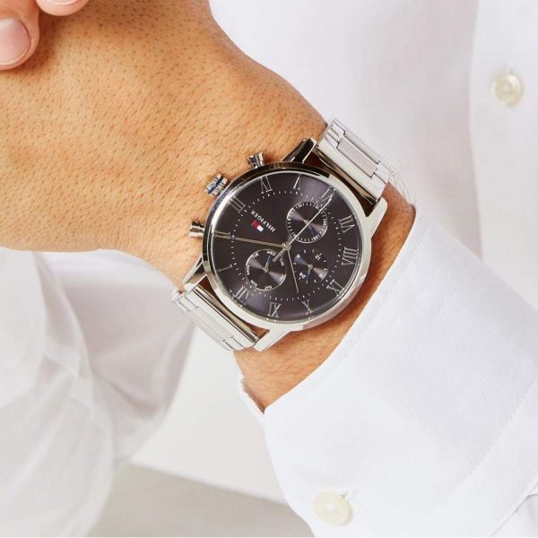 שעון יד טומי הילפיגר לגבר רצועת מתכת כסופה רקע אפור כהה דגם 1791397 על יד